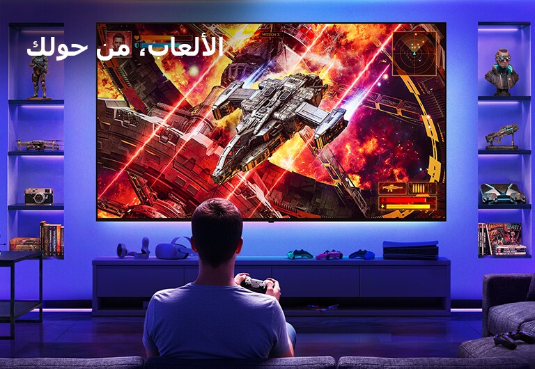 تلفزيون LG Ultra Big TV مثبت على الحائط في غرفة ألعاب مضاءة بالنيون، حيث تعرض شاشة كبيرة مشهد معركة في مساحة نابضة بالحياة بينما يجلس اللاعب أمام الشاشة، مما يوضح تجربة ألعاب غامرة وجذابة.