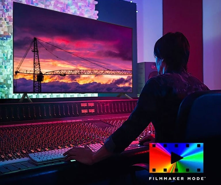 يظهر رجل في استوديو تحرير مظلم ينظر إلى تلفزيون LG TV الذي يعرض غروب الشمس. يوجد في الجزء السفلي الأيمن من الصورة شعار وضع FILMMAKER Mode.