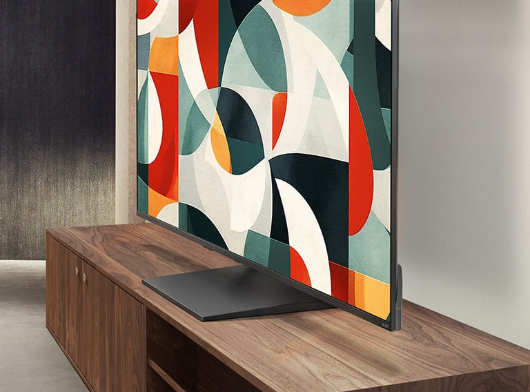 تلفزيون LG QNED TV يقف فوق درج تلفزيون في غرفة معيشة عصرية. يصور تلفزيون LG QNED TV خلفية تجريدية بالألوان الأخضر والأحمر والبرتقالي.