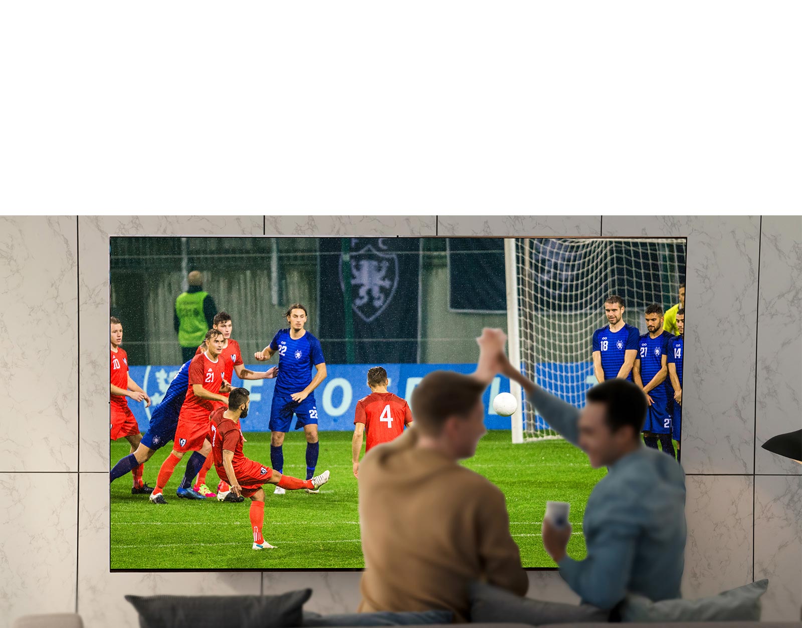 أناس يشاهدون الألعاب الرياضية على شاشة التلفزيون في غرفة المعيشة على شاشة فائقة الحجم