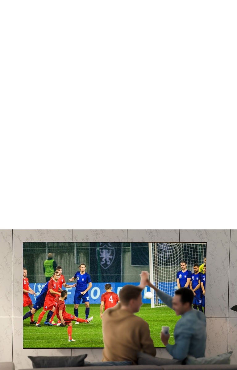 أناس يشاهدون الألعاب الرياضية على شاشة التلفزيون في غرفة المعيشة على شاشة فائقة الحجم