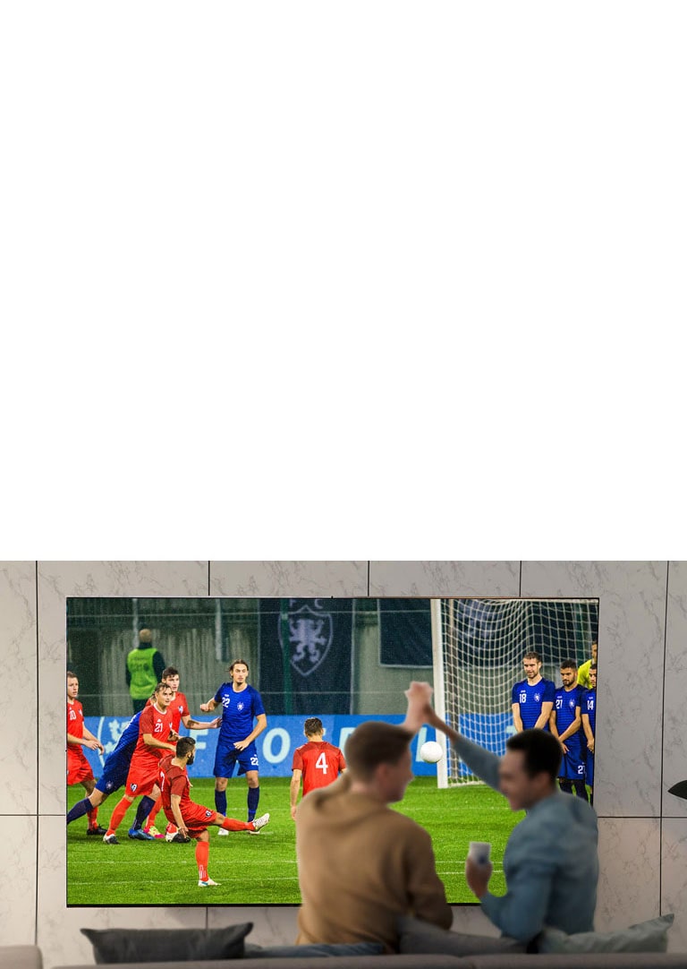 أناس يشاهدون الألعاب الرياضية على شاشة التلفزيون في غرفة المعيشة على شاشة فائقة الحجم