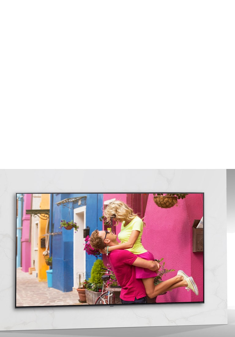 شاشة تلفزيون تعرض أحد المشاهد من فيلم رومانسي ملون يظهر رجلا وامرأة يتعانقان.