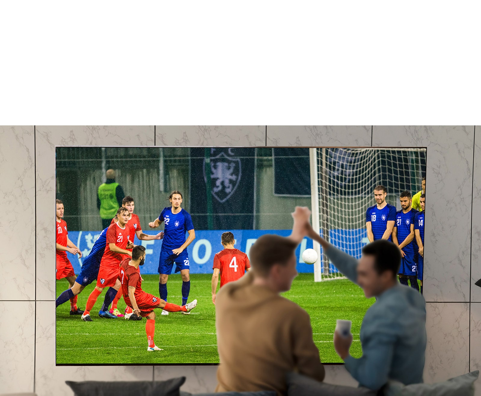 أناس يشاهدون الألعاب الرياضية على شاشة التلفزيون في غرفة المعيشة على شاشة فائقة الحجم