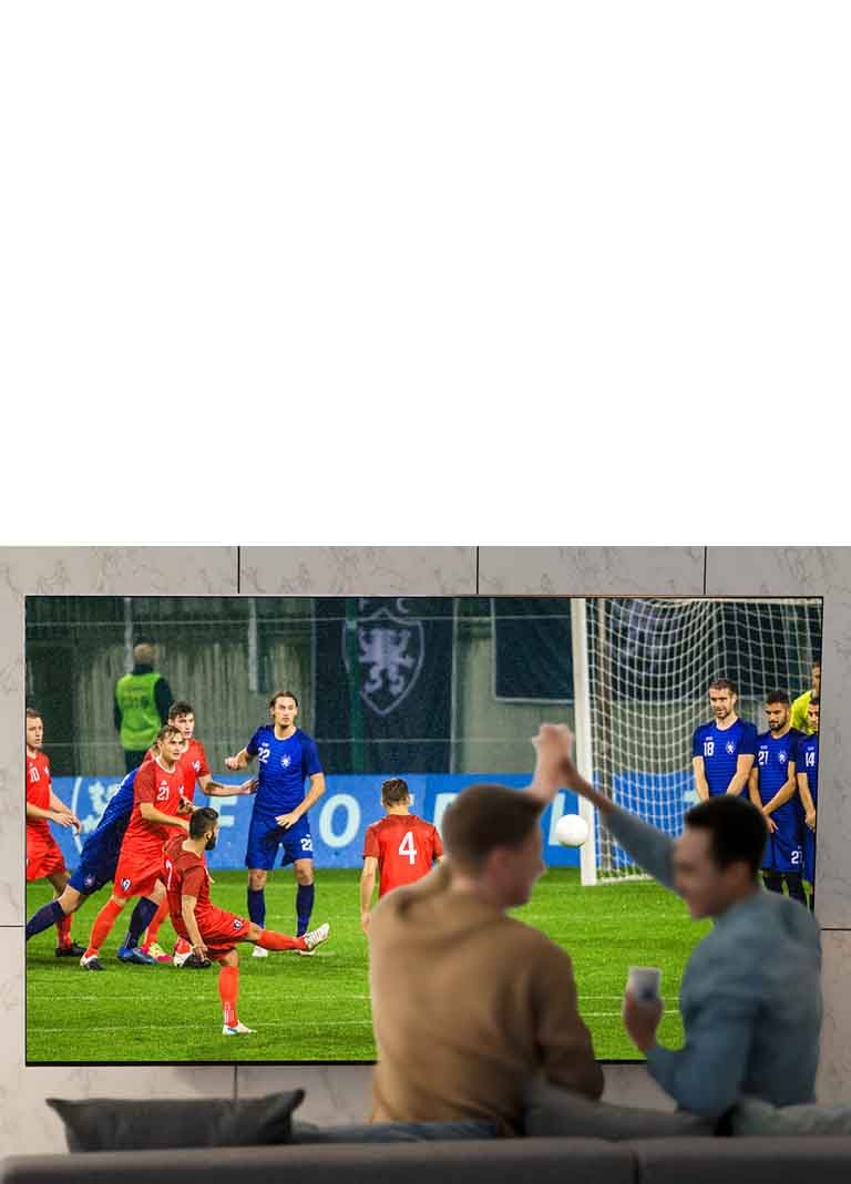 أناس يشاهدون الألعاب الرياضية على شاشة التلفزيون في غرفة المعيشة على شاشة فائقة الحجم