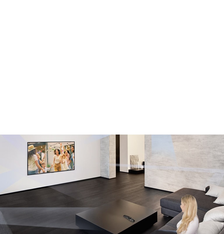 امرأة تجلس في غرفة معيشة رحبة تتميز بديكور داخلي بسيط وتشاهد أشخاصًا يرقصون على شاشة التلفزيون