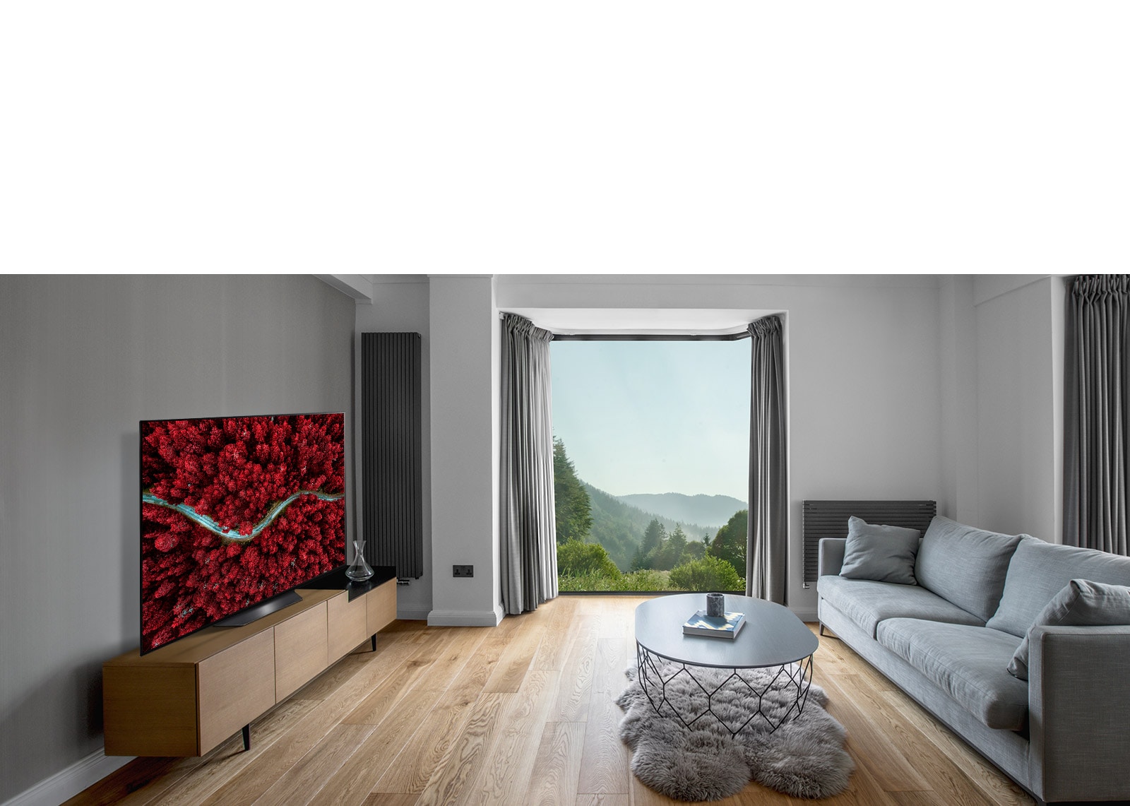 غرفة معيشة بها أريكة وتلفزيون يعرض صورة جودة جوية للطبيعة الخلابة