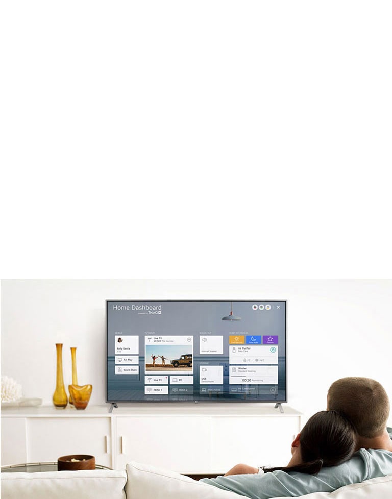 رجل وامرأة يجلسان على أريكة في غرفة المعيشة مع ظهور اللوحة الرئيسية على شاشة التلفزيون.