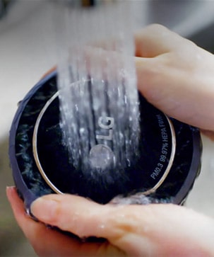 تمسك يد المرأة بجوانب المرشح بينما يتم غسله بالماء تحت صنبور جارٍ.