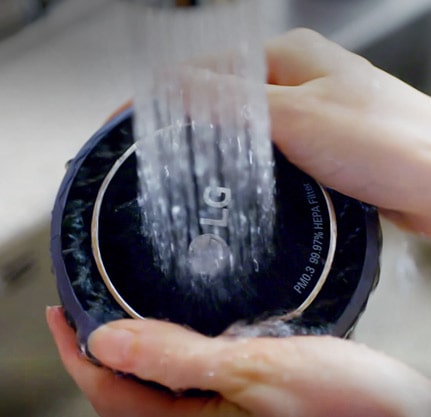 تمسك يد المرأة بجوانب المرشح بينما يتم غسله بالماء تحت صنبور جارٍ.