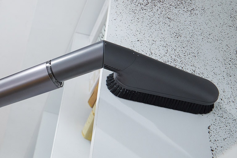 تظهر الأداة متعددة الزوايا وهي تزيل الغبار عن الرف العلوي لرف الكتب.