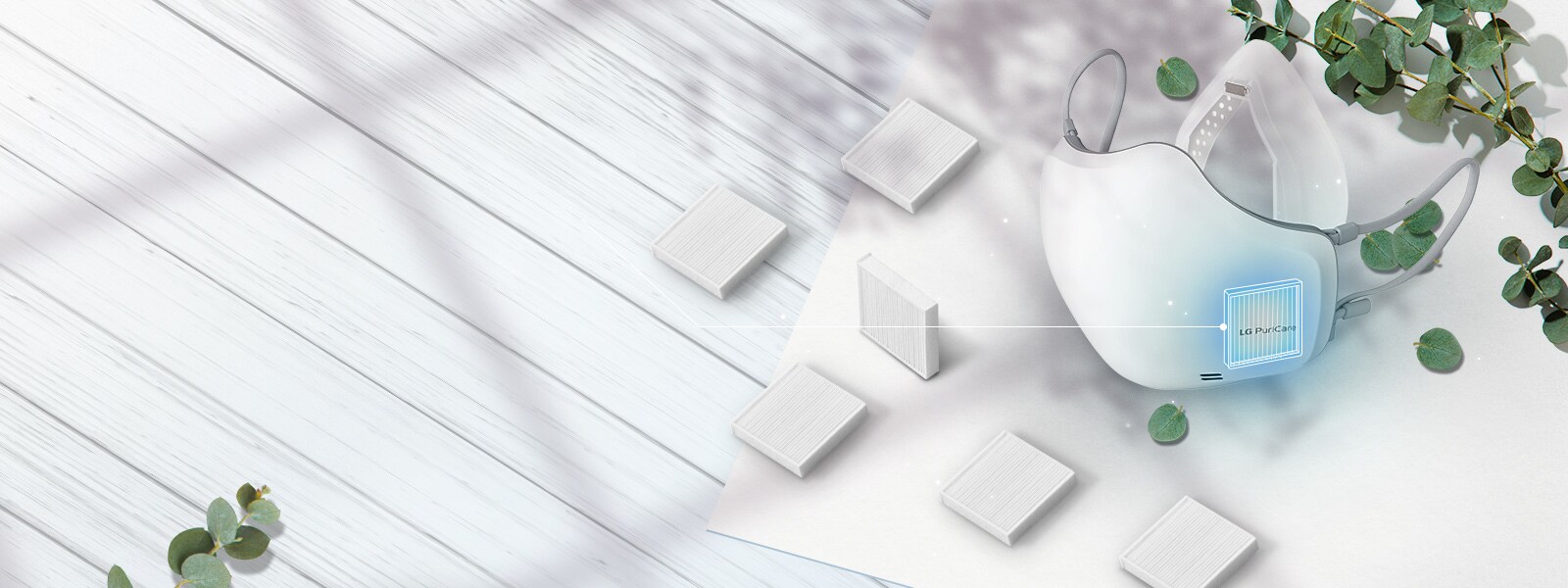 يتم عرض جهاز تنقية الهواء القابل للارتداء LG PuriCare بزاوية من الأعلى مع فلاتر HEPA من الفئة H13 منتشرة على الطاولة حوله.  يتم تمييز مكان إدخال الفلتر على القناع بمربع أزرق. 