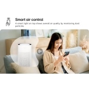 LG جهاز تنقية الهواء PuriCare™ AeroHit لتغطية 32 م2, امرأة تجلس على أريكة، وتتحكم في جهاز تنقية الهواء LG PuriCare باستخدام تطبيق LG ThinQ على هاتفها الذكي. النص مكتوب عليه "التحكم الذكي في الهواء: يُظهر الضوء الذكي الموجود بالأعلى جودة الهواء العامة من, AS35GGW10, thumbnail 5