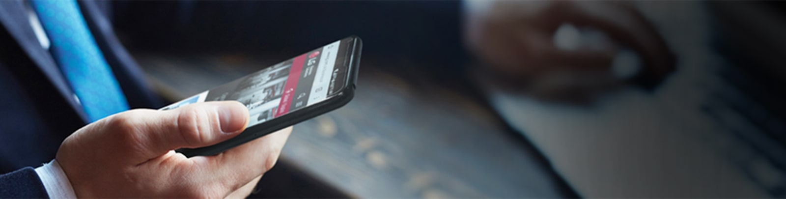 صورة لرجل يحمل هاتفًا ذكيًا مع صفحة ويب LG على الشاشة. 