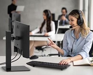 امرأة ترتدي سماعة رأس وهي تعمل وتنظر في شاشة.	