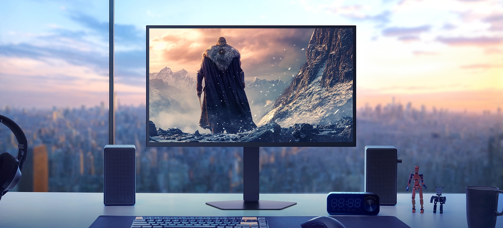شاشة LG UltraGear 27GX790B موضوعة على مكتب يطل على مشهد مدينة عند غروب الشمس، وتعرض مشهدًا من لعبة خيالية يظهر فيه شخصية مقنّعة تقف وسط جبال مغطاة بالثلوج. يحيط بالشاشة مكبرات صوت ولوحة مفاتيح وساعة وتماثيل صغيرة وكوب