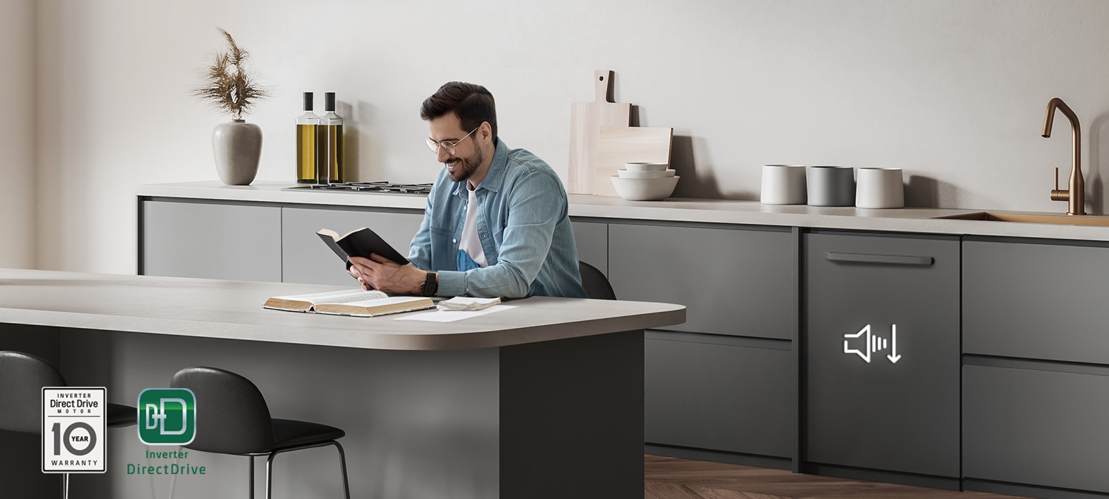 رجل يقرأ كتاباً في جزيرة المطبخ بينما تعمل غسالة أطباق LG المدمجة في الخلفية.
