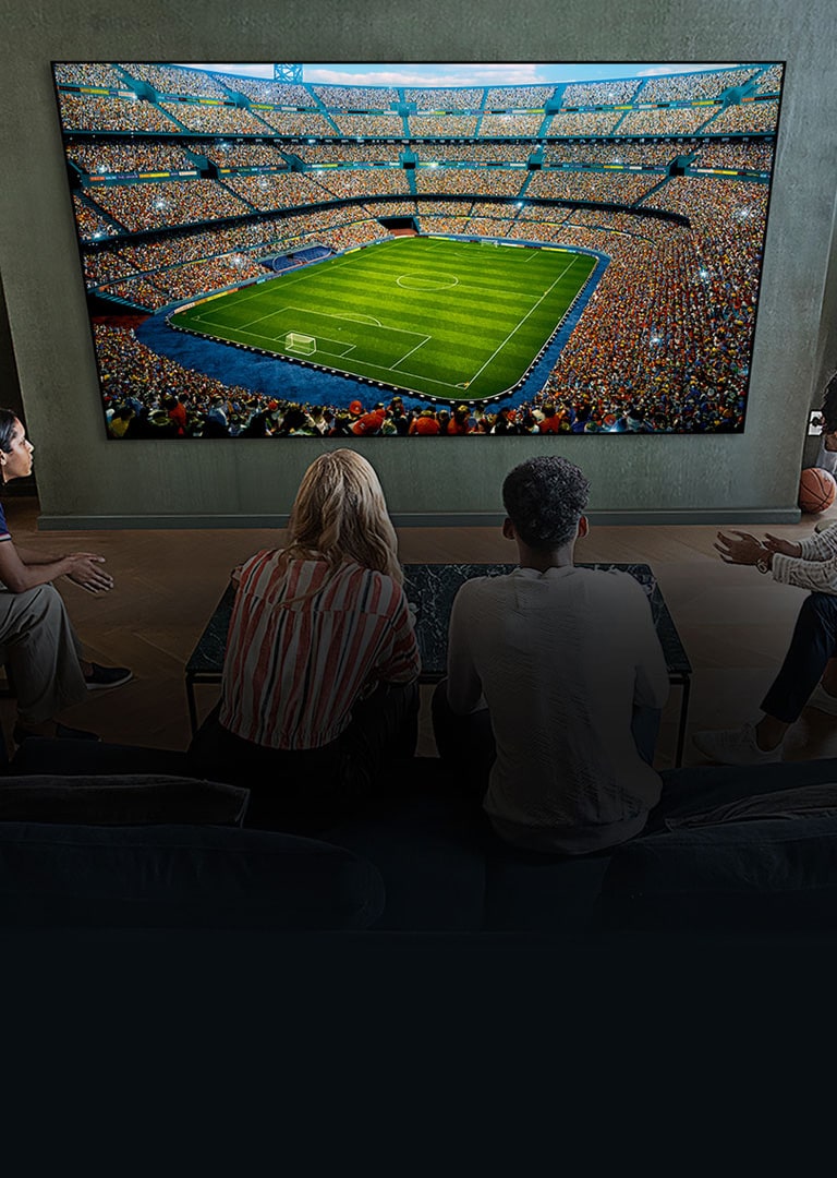 People watching a soccer game on a large TV screen in the living room