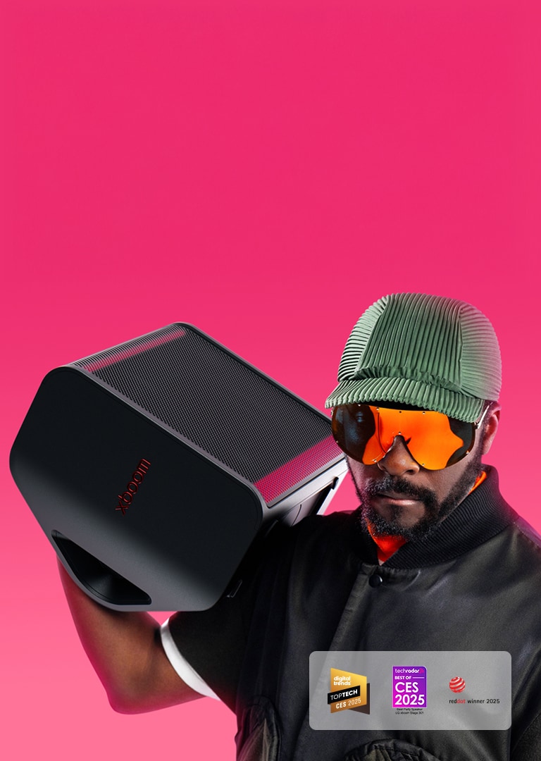 will.i.am يرتدي زيًا أسود ويمسك جهاز xboom Stage 301 فوق كتفه الأيمن
