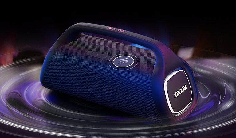 مكبر الصوت XBOOM GO XG9 من إل جي موضوع على الطاولة. زر تعزيز الصوت بحجم مكبر ومؤثرات الموجات الصوتية تحت مكبر الصوت. شغِّل الفيديو.