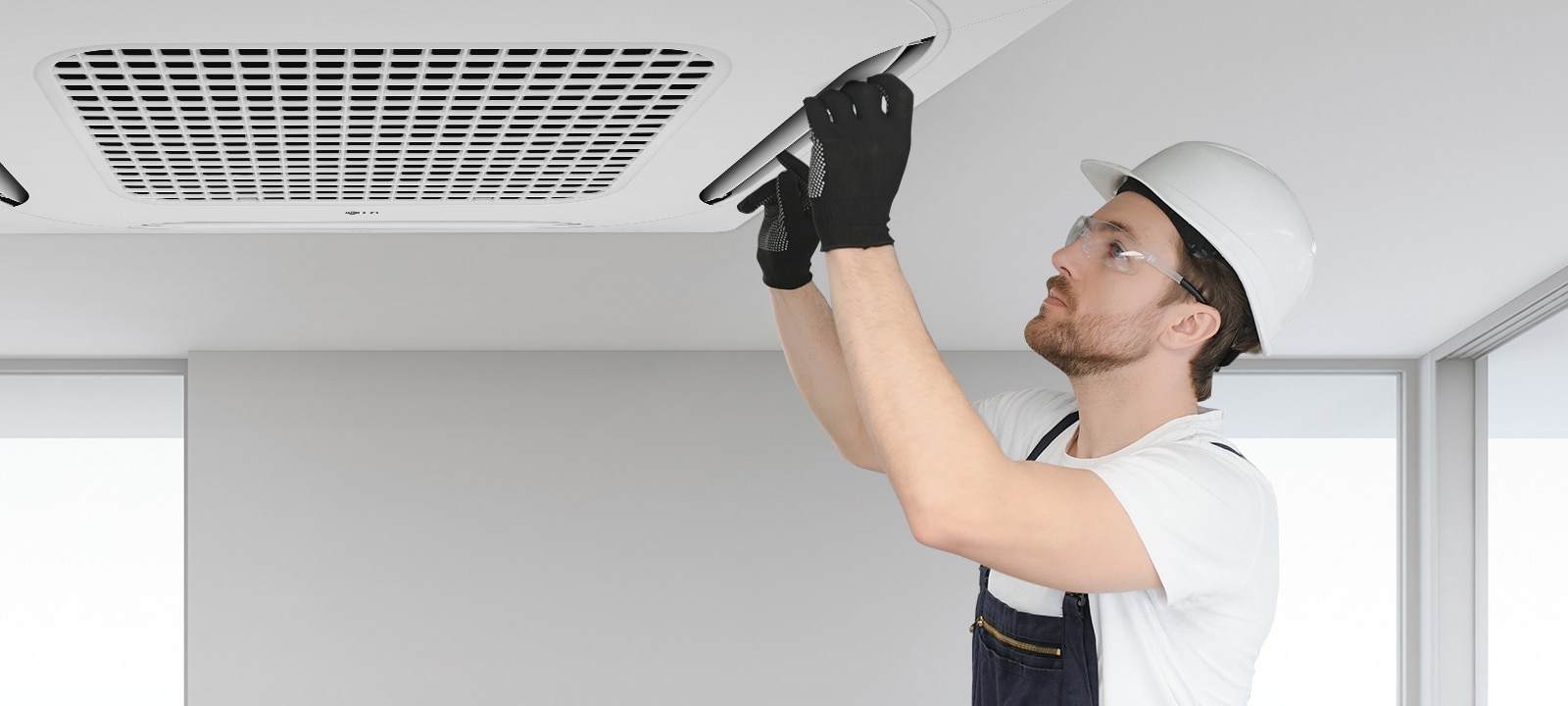 يقوم أحد الفنيين بتركيب أو صيانة وحدة مُكيِّف LG ceiling-mounted cassette، وهو يرتدي ملابس السلامة.