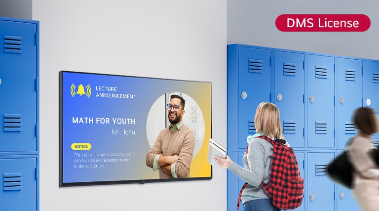 تُظهِر هذه الصورة طالبًا يشاهد محتوى على شاشة لافتات رقمية في مدخل المدرسة. يقول الإشعار المعروض "الرياضيات للشباب" (جلسة خاصة للرياضيات)، ويوجه الطلاب للتجمع في قاعة المحاضرات.