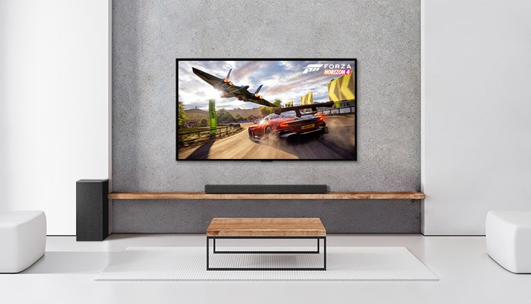 يوجد مضخم صوت ومكبر صوت وتلفزيون في غرفة المعيشة البيضاء. سيارة تقود وسفينة فضاء معروضة على شاشة التلفزيون.