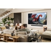 LG تلفزيون LG QNED evo AI QNED9M الذكي مقاس 86 بوصة بدقة 4K 144Hz ومدعوم بجهاز التحكم AI Magic remote وواجهة webOS25 طراز عام 2025 , عائلة تجلس على أريكة في مواجهة تلفزيون LG QNED TV مثبت على جدار فوق مكبر الصوت LG Soundbar. يظهر صندوق Zero connect box داخل طاولة القهوة., 86QNED9MA6A, thumbnail 15