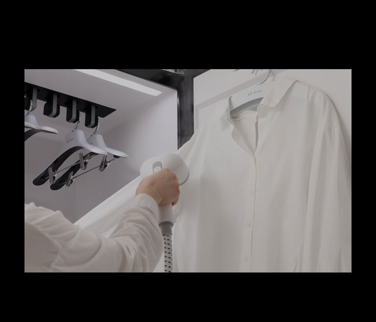 شخص يستخدم مكبس EZ Fit PantsPress™ متعدد الصفائح في LG Styler لإزالة التجاعيد واستعادة الطيات إلى البنطال.