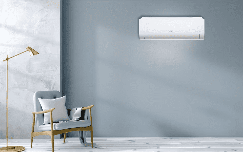 Sleek white LG DualCool AC on a light blue wall in a modern room with a grey armchair and gold lamp. Efficient home cooling