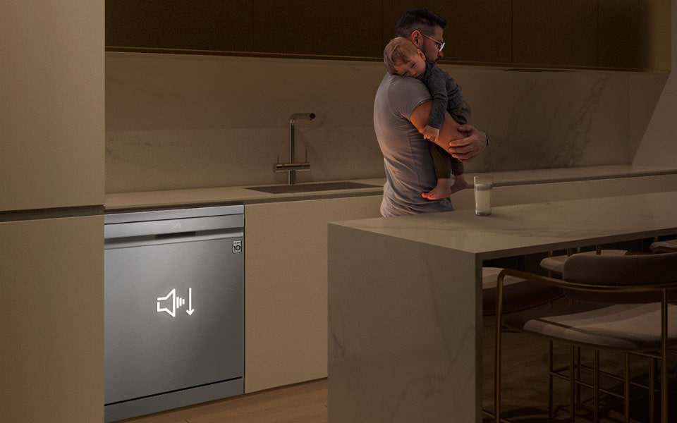 رجل يحمل طفلاً نائماً في مطبخ بجوار غسالة أطباق إل جي هادئة ومنخفضة الضوضاء والاهتزاز.