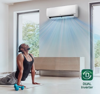 A man exercising under an air conditioner that is fast cooling the space.