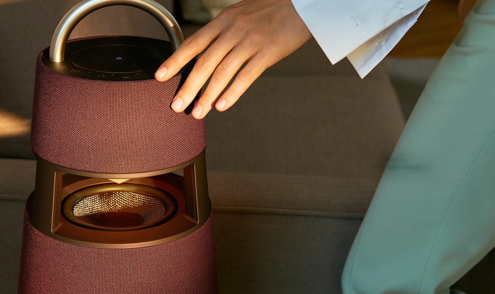 Image of a woman touching the exterior of a burgundy-colored XBOOM 360 product.