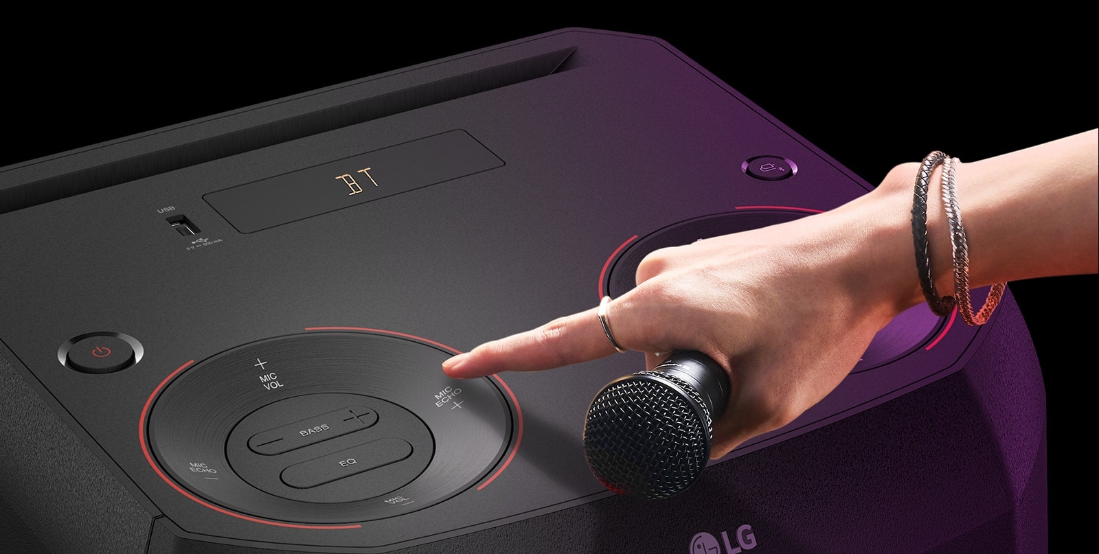LG XL2S A hand holding a microphone tries to press the MIC ECHO button on the top of the speaker.