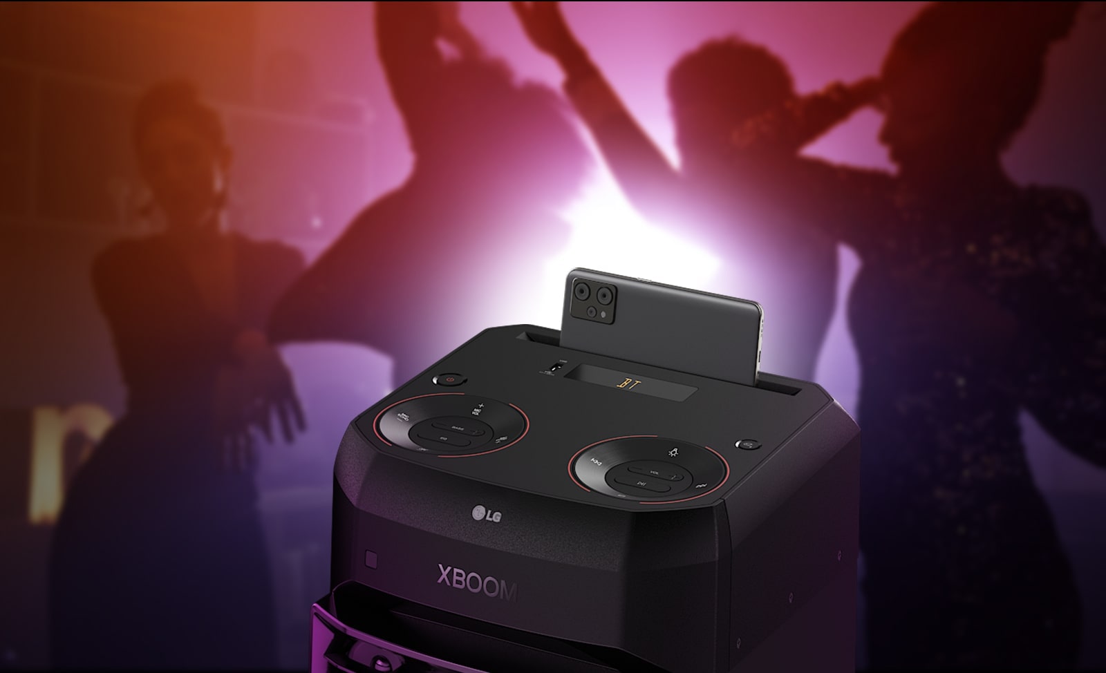 LG XL2S A close-up view of the top of LG XL2S, highlighting on the phone cradle. A smartphone is placed on the phone cradle. Behind, there are silhouettes of people dancing.