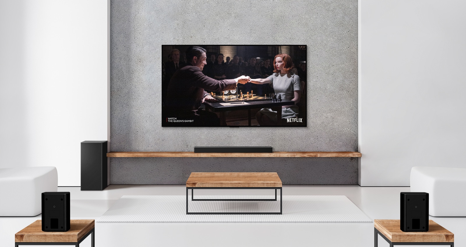 A set of 2 rear speakers, subwoofer, and a soundbar, and TV are in a white living room. A woman and a man are playing chess on TV screen. 