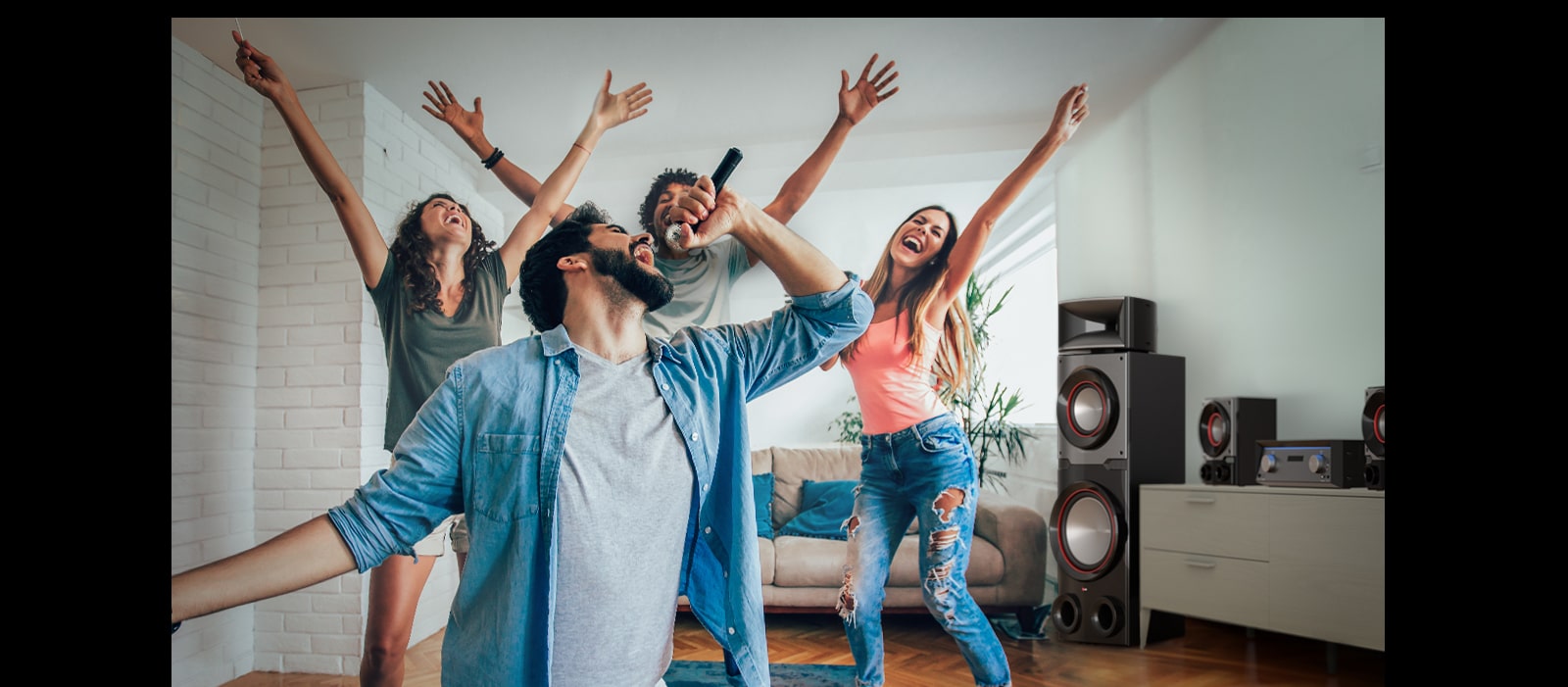 A group of people are enjoying karaoke in the living room, LG MR11 is placed beside them.