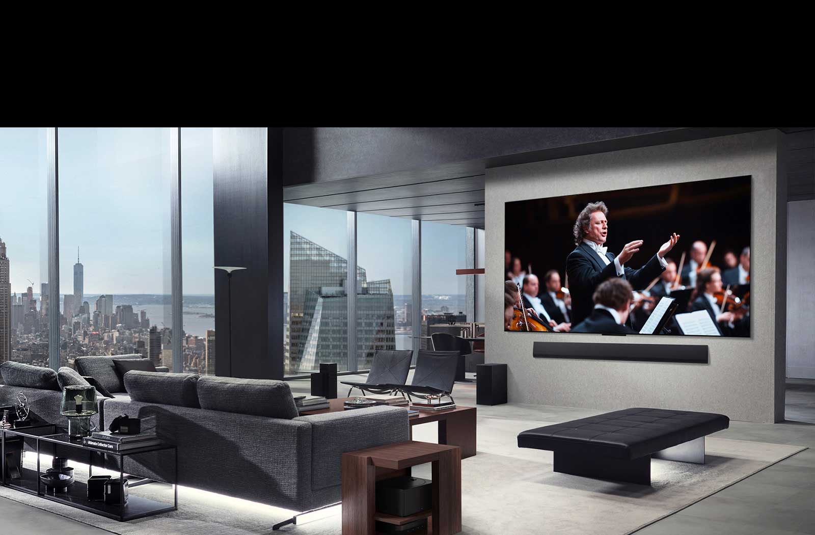 Living room with an LG True Wireless TV and LG Soundbar that's wall-mounted. The Zero Connect Box is barely seen under a side table by the couch, showing how it can easily be placed anywhere. The whole living room's layout is visually neat and tidy.