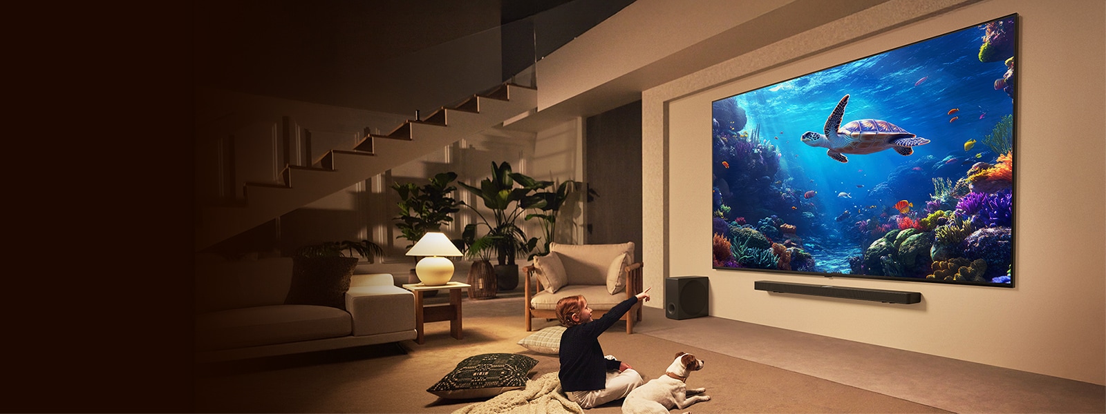 A huge LG QNED TV and LG Soundbar is mounted on the wall. A little girl and her puppy are watching an underwater scene on the TV. The sheer size of the TV makes the content feel even more immersive. 