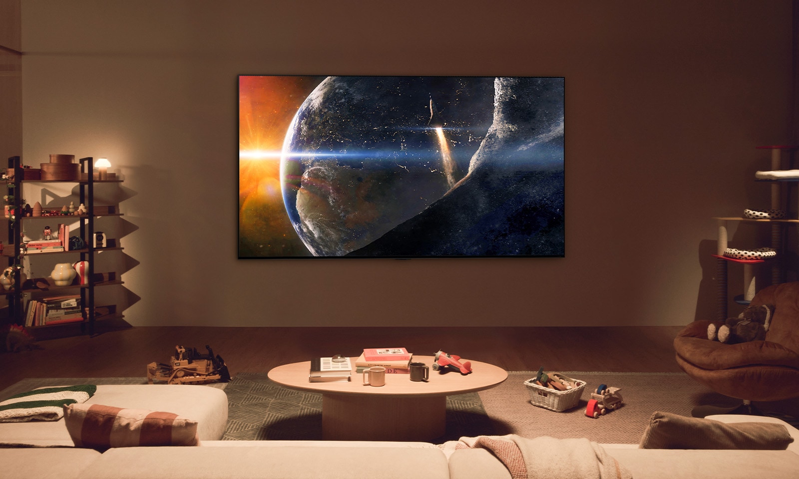 A family sat on the floor of a low-lit living room by a small table, looking up at an LG TV mounted on the wall showing the Earth from space.