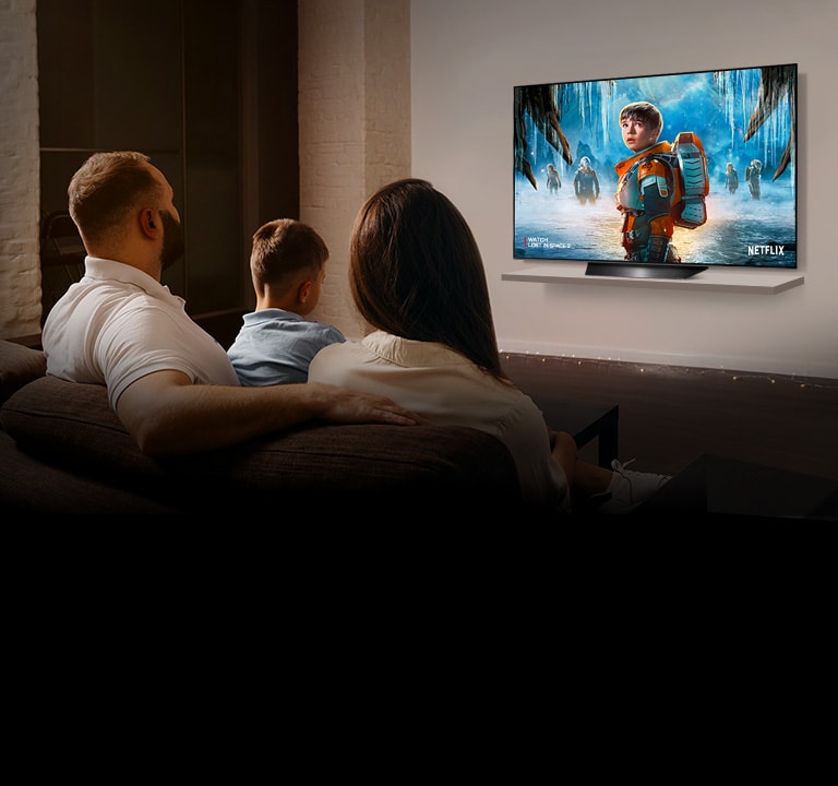 Couple sitting on a sofa in the living room watching a romantic movie on TV