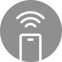 A woman sitting on the couch and drinking tea is giving orders to her washing machine through her AI speaker.