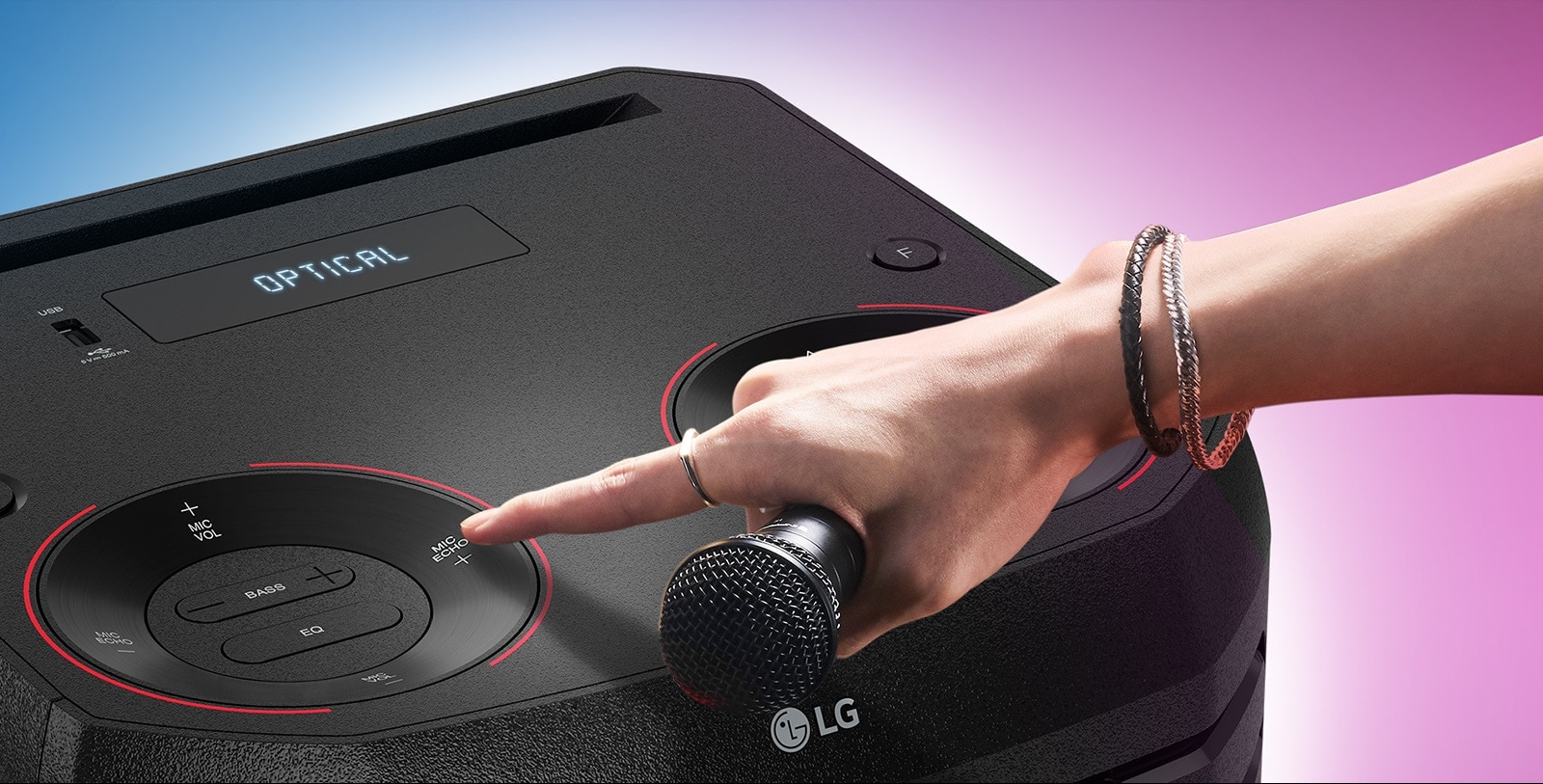 A hand holding a microphone tries to press the Mic echo button on the top of LG XBOOM.