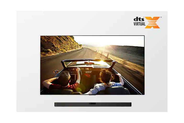 TV and Soundbar together in full view. TV shows a couple in an open roof car on the road driving into the sunset. 