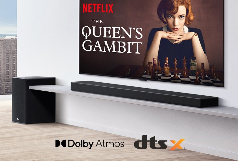 TV is on the wall. A poster of a TV show is on TV screen. LG Soundbar is right below TV on a white shelf with a sub-woofer right next. Dolby Atmos and DTS:X logo shown on middle bottom of image.