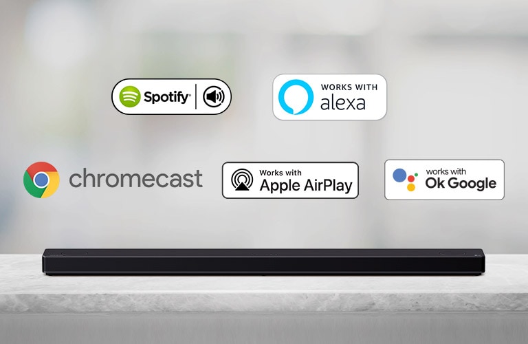 There is a soundbar placed on a gray shelf and there are AI platform logos, in order of Spotify, Alexa, Chromecast, Apple Airplay, and OK Google from left to right.