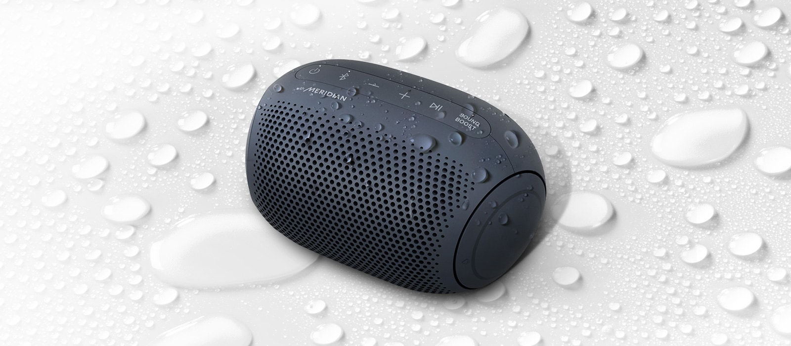 On a white background, LG XBOOM Go is facing up to the left. There are water droplets on and underneath LG XBOOM Go.