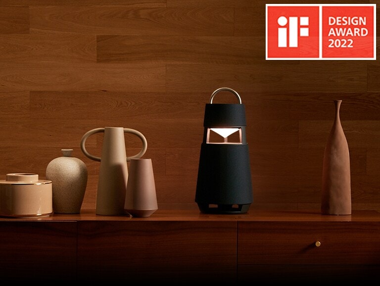 Image of the XBOOM 360 with sculptures on a shelf in a wood-toned interior background.