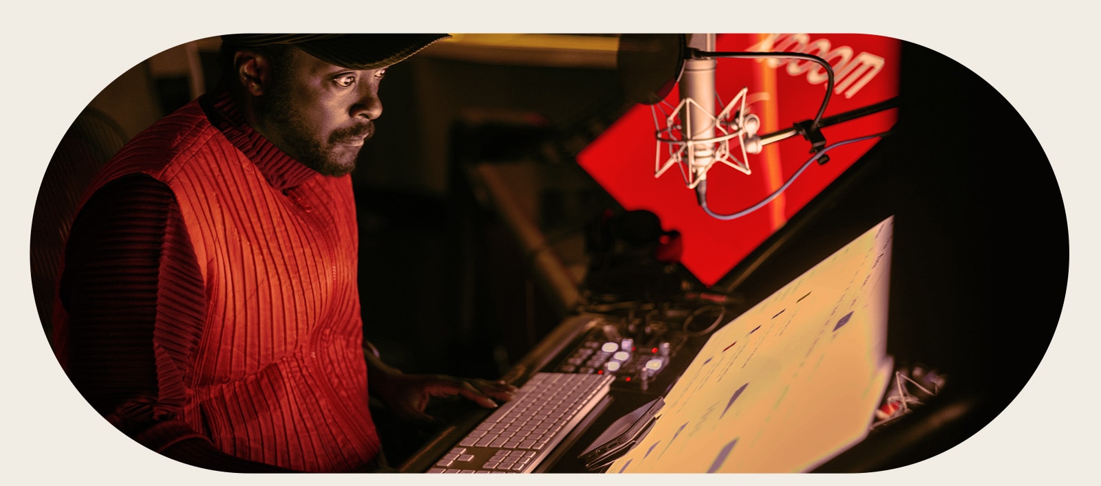 will.i.am is working in studio looking at a screen placed below a mic.