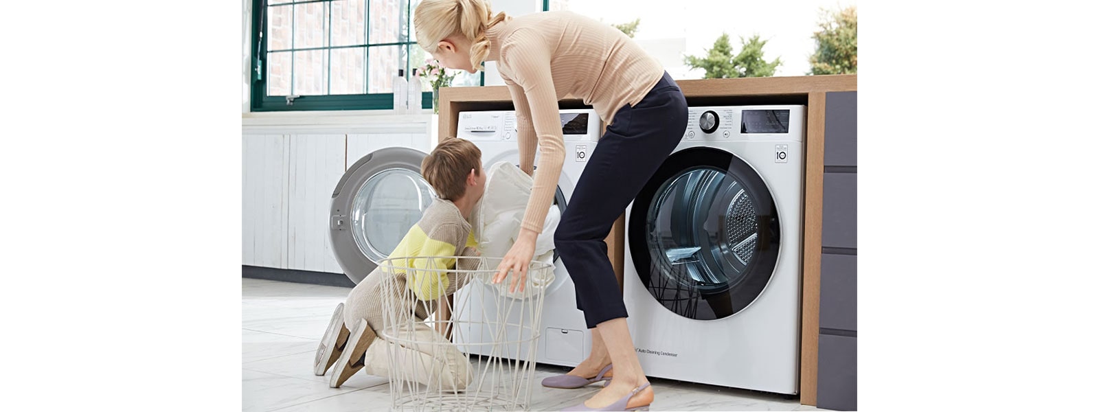 a picture containing an adult and child in a kitchen setting with a white LG washing machine and a white LG tumble dryer